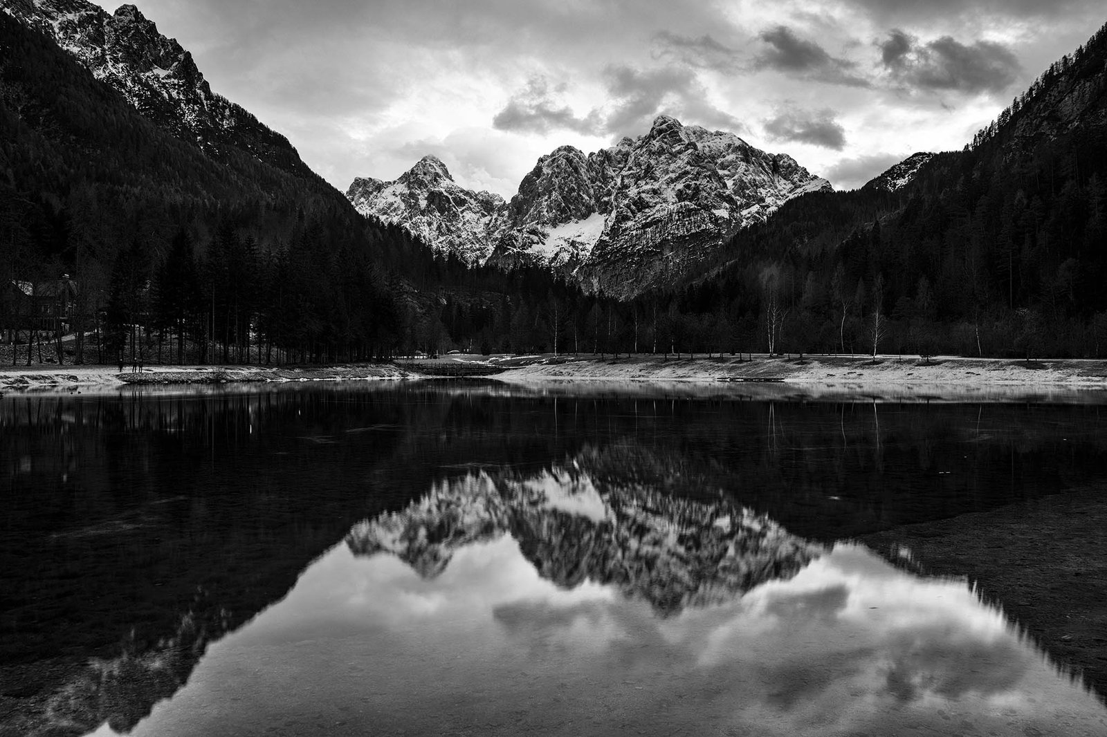 Black and white image of the Julian Alps seen across Lake Jasna in winter, near Kranjska Gora, Slovenia